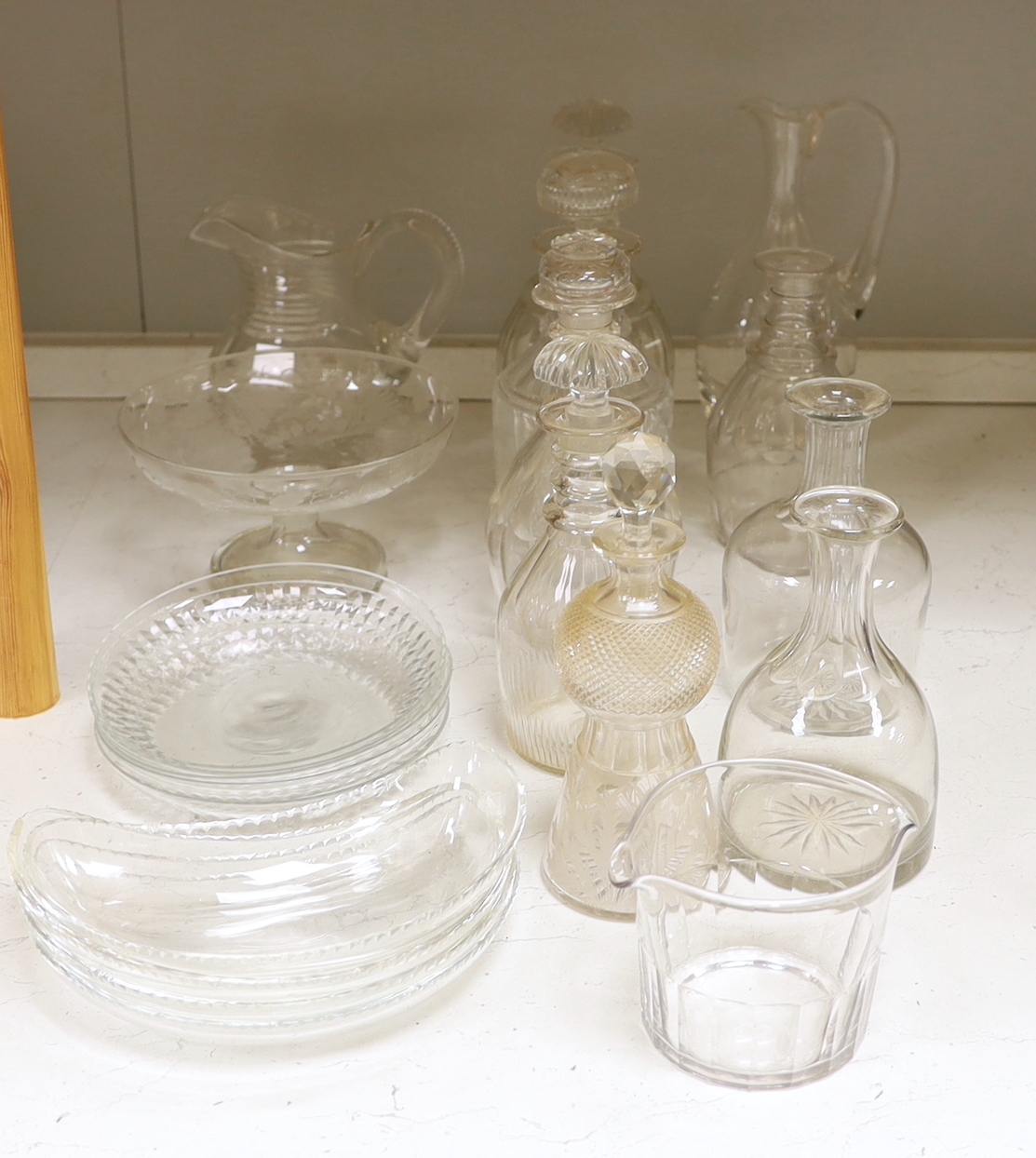 A collection of cut glass decanters and other glassware including five decanters with stoppers, three carafes, two jugs, five shallow round dishes, a pedestal dish, four Crescent dishes and a rinser, tallest 25cm